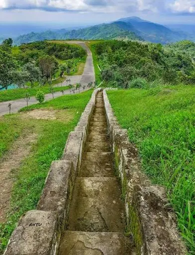A stone stairway running along a green ridge towards the mountains