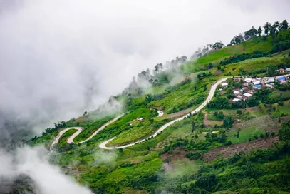A mountain road curving through misty green hills in Bandarban