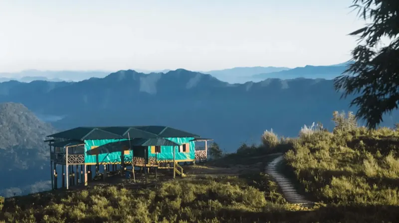 A turquoise hilltop cottage looking out over layers of blue mountains