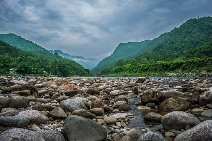 Stones in a shallow river between steep green hills