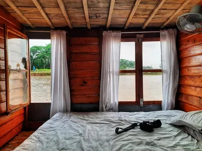 A houseboat cabin with windows open onto the haor